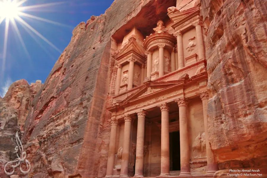 A front-facing view of the Treasury building in Petra carved into red sandstone cliffs.