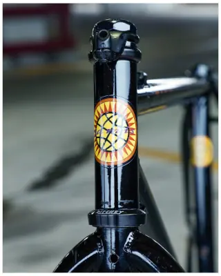 A close-up shot of the front of a black bike frame. There is a yellow globe-type logo on the front of the tubing.