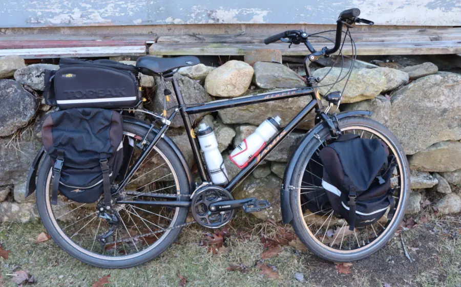 A mountain bike all kitted out with fenders, racks, bags, lights, and waterbottles.
